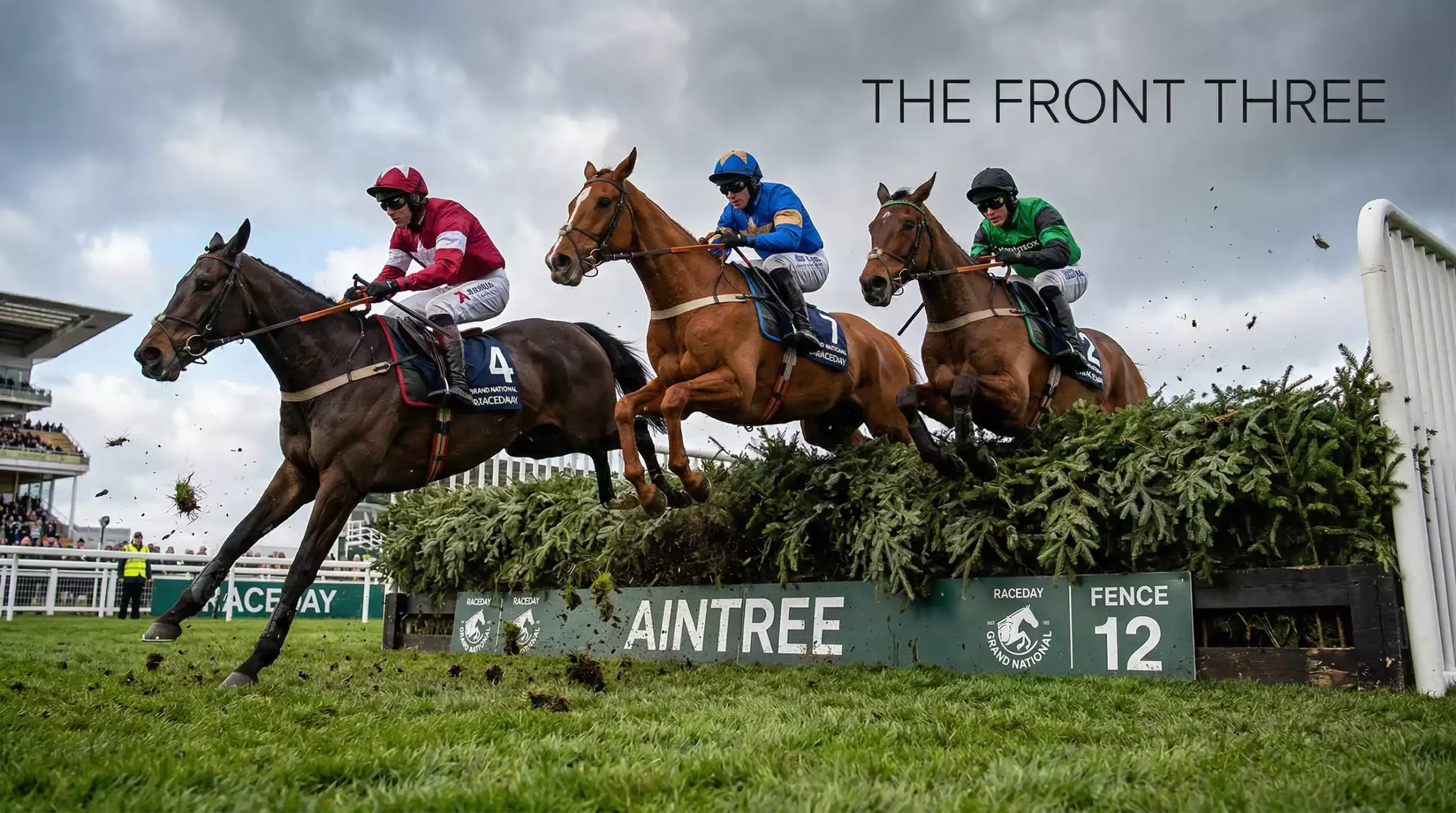 Three horses jumping a fence in close formation during a steeplechase race