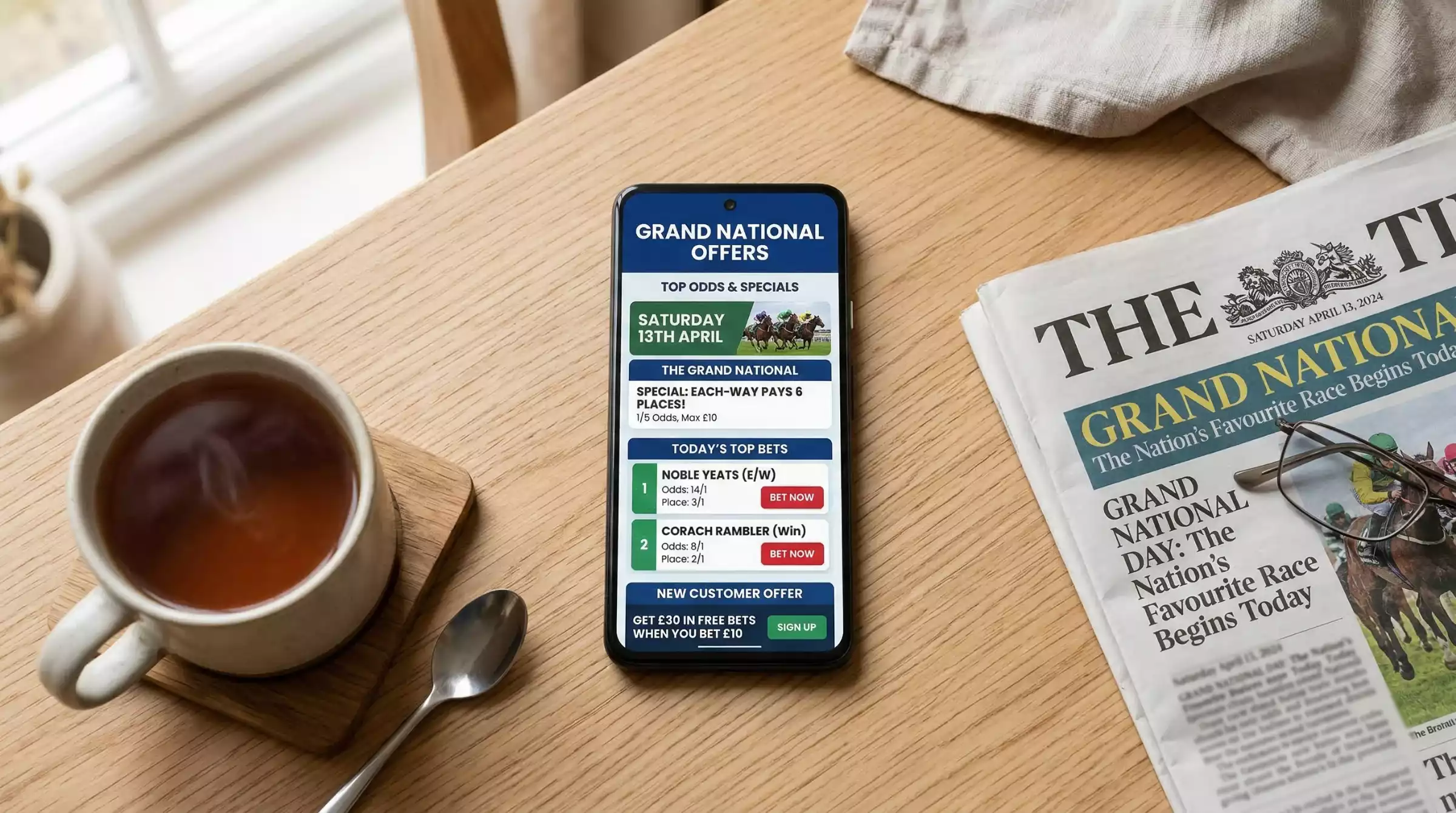 A smartphone displaying Grand National betting offers next to a cup of tea on a kitchen table